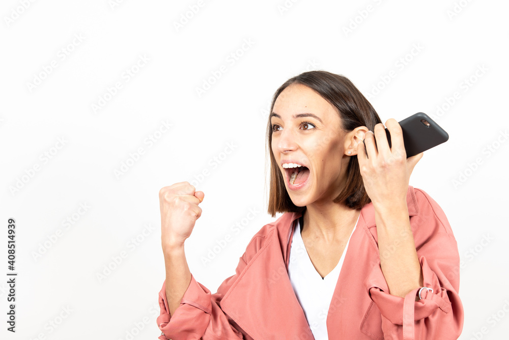 Excited happy latin girl celebrating the good news or results while holding her mobile phone. Excited happy latin girl celebrating the good news or results while holding her mobile phone.