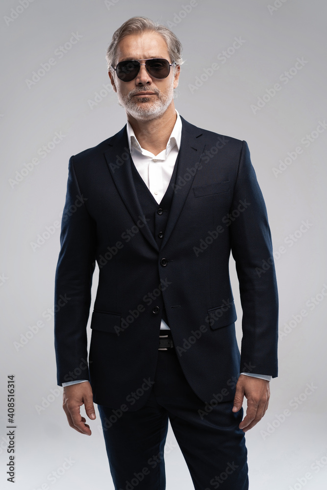 Portrait of a respectable mature man in a suit and sunglasses on a gray background. Businessman portrait. Copy space Portrait of a respectable mature man in a suit and sunglasses on a gray background. Businessman portrait. Copy space