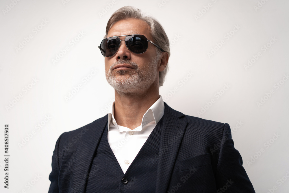Portrait of a respectable mature man in a suit and sunglasses on a gray background. Businessman portrait. Copy space Portrait of a respectable mature man in a suit and sunglasses on a gray background. Businessman portrait. Copy space