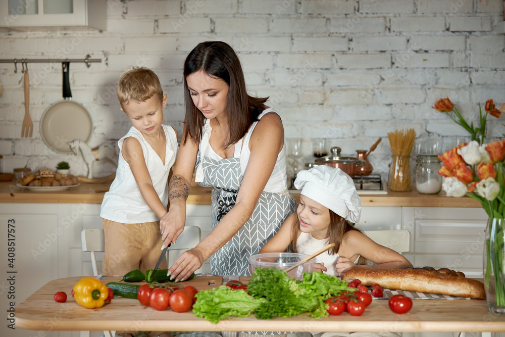 Mom cooks lunch with the kids. A woman teaches her daughter to cook from her son. Vegetarianism and healthy natural food
