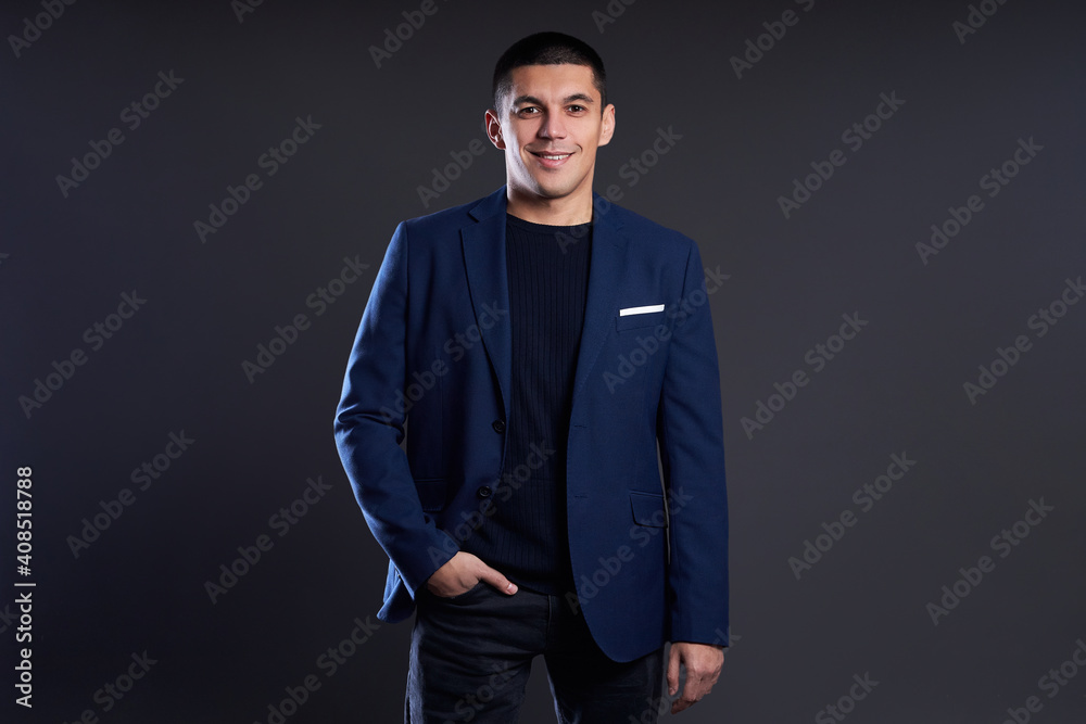 Portrait of a businessman in blue jacket on dark background in studio. man with short haircut. Young confident manager smiles