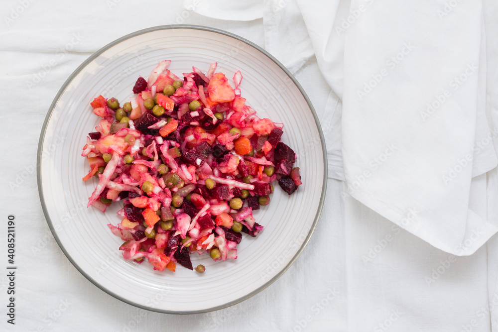 Russian traditional salad with vegetables - vinaigrette on a plate on a table on a cloth. Top view. Copy space Russian traditional salad with vegetables - vinaigrette on a plate on a table on a cloth. Top view. Copy space