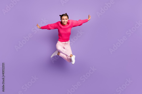 Full size photo of positive pretty excited young woman jump up air hands fly wings isolates on purple color background