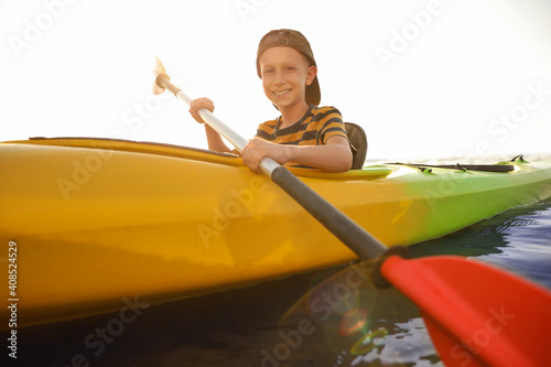 Happy little boy kayaking on river. Summer camp activity