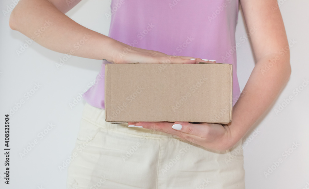 Cardboard box with a parcel in female hands. Concept of safe home delivery in a pandemic. Copy space. An order came from an online store Cardboard box with a parcel in female hands. Concept of safe home delivery in a pandemic. Copy space. An order came from an online store