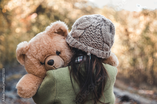 Little girl hugs her bear on a background of nature, autumn, durba.