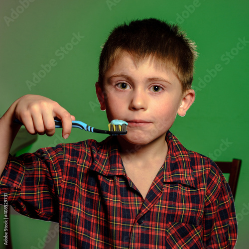 A boy in pajamas brushes his teeth, oral hygiene from childhood is especially important. photo