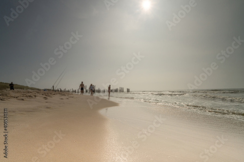 Seascape with blurred people walking in the background. Silhouette of people on the beach and in the sea, people fishing. Vintage style photo. focus on foreground