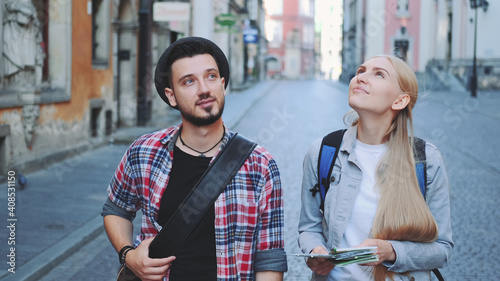 Happy young tourist couple with map walking and looking at old city architecture. Sightseeing in beautiful european city. © art24pro