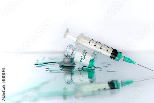 Development and creation of a coronavirus vaccine COVID-19. Ampoule and syringe. Spilled liquid on white reflective surface. Healthcare and medical concept.