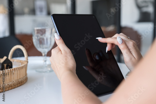 Brunette Caucasian woman in white blouse and black skirt working via internet using tablet. Work from home concept. Space for text
