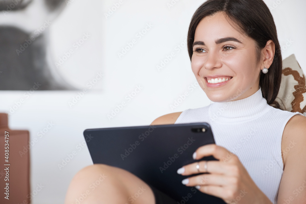 Brunette Caucasian woman in white blouse and black skirt working via internet using tablet. Work from home concept. Space for text Brunette Caucasian woman in white blouse and black skirt working via internet using tablet. Work from home concept. Space for text