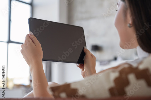 Brunette Caucasian woman in white blouse and black skirt working via internet using tablet. Work from home concept. Space for text