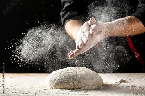 Photo of flour and men hands with flour splash. Cooking bread. Kneading the Dough. Isolated on dark background. Empty space for text photo