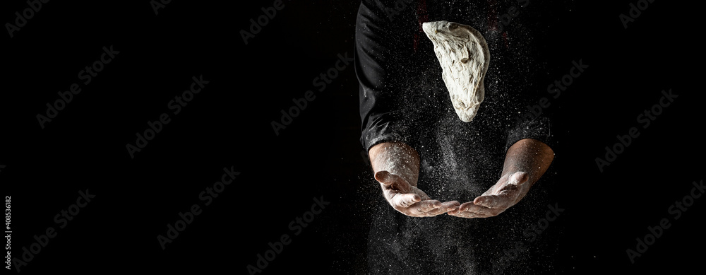 Beautiful and strong men's hands knead the dough make bread, pasta or pizza. Powdery flour flying into air. chef hands with flour in a freeze motion of a cloud of flour midair