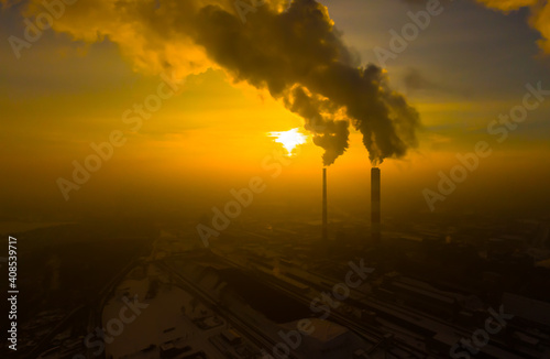 Power Plant emissions seen above the city during sunrise. Environmental pollution. Factory pipe polluting air.Panorama sunset. Smoking pipes Aerial view,