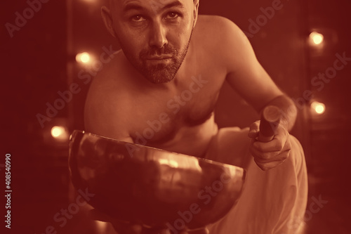 Tibetan singing bowl, a monk in yellow pants meditates and plays the musical bowl, Buddhism, religion photo