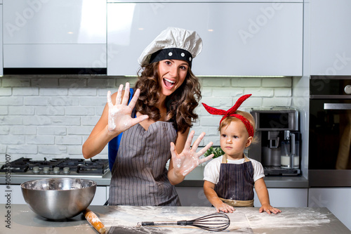 Mother and daughter in the kitchen with flour hands.