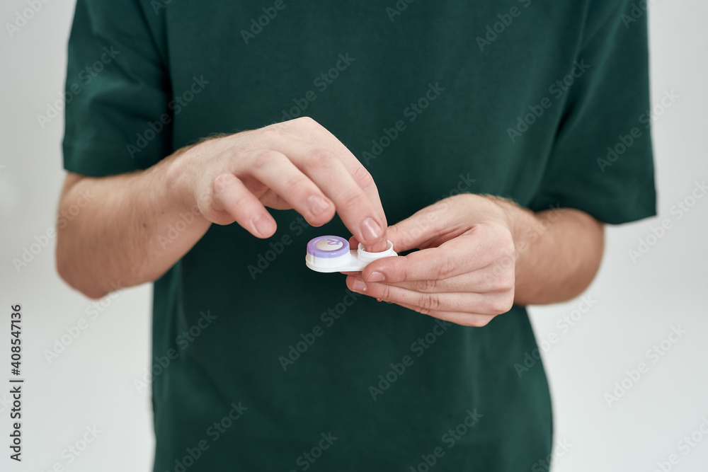 Man taking out contact lenses from storage box Man taking out contact lenses from storage box