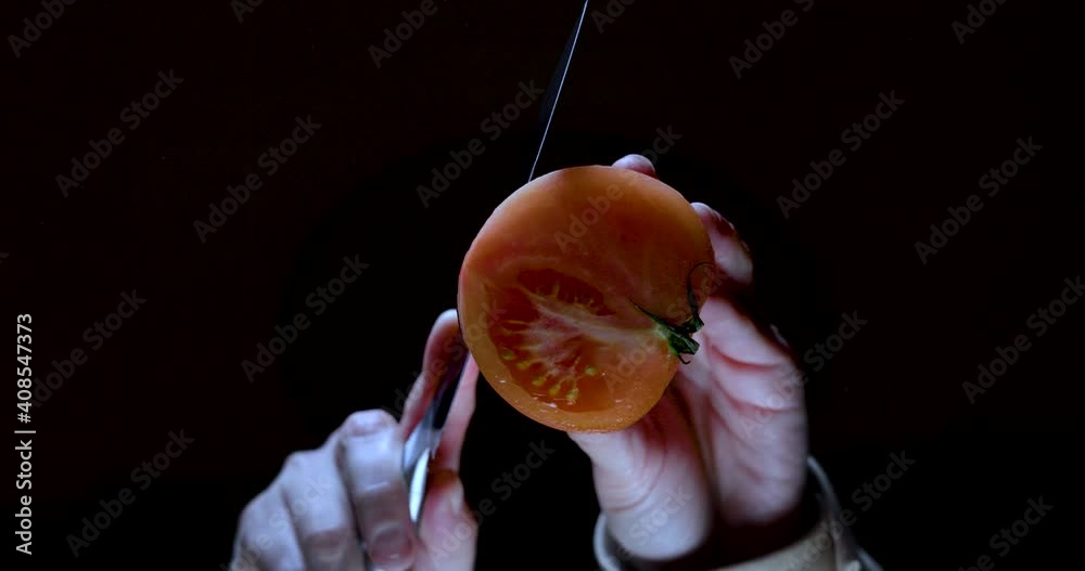 Healthy food bottom view. Cutting a fresh tomato on a black background
