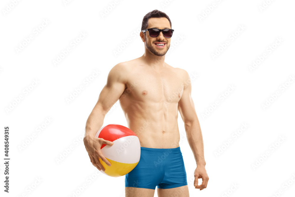 Young man in swimming shorts holding an inflatable ball