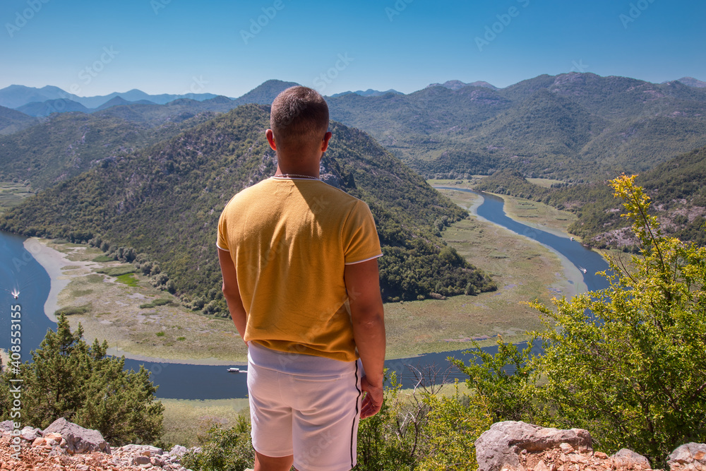 Traveller man on the rock at the top of panoramic of lake skadar in Montenegro.  Holiday concept.