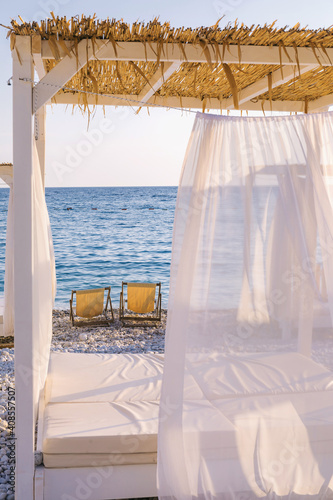 Beautiful canopies or baldachine at sea beach at the sunset. Vacation and relaxation concept.