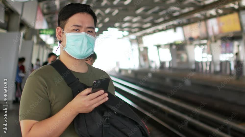 POV of a man wearing mask protect from corona virus Covid19 while using mobile phone waiting for skytrain approaching