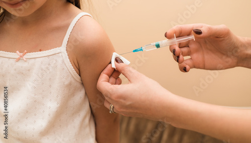 Little girl in the doctor's office is vaccinated. Syringe with vaccine against covid-19 coronavirus, flu, infectious diseases. Injection after clinical trials for human, child. Medicine concept.