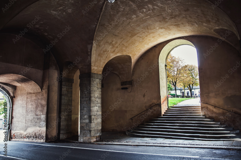 Pedestrian tunnel, old stone arched doorway and road in a European city.