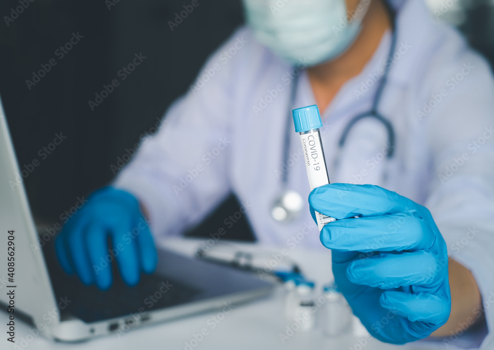 Fototapeta premium Doctor or scientist in laboratory or hospital holding a liquid vaccines and using laptop for research ,diseases,medical care,science. Fight against virus covid-19 corona virus concept.