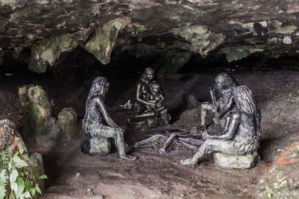 Obraz premium FURONG ZHEN, CHINA - AUGUST 11, 2018: Sculptures of prehistoric people in a cave under the waterfall in Furong Zhen town, Hunan province, China