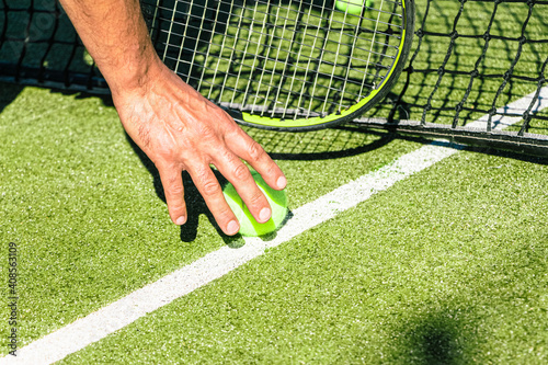 Man picking up a tennis ball from the ground