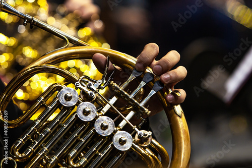 Hands of a musician playing the French horn in the orchestra close up