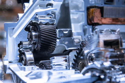 Motor of the electric car with powertrain and power connections closeup. Blue toned. EV car at maintenance.