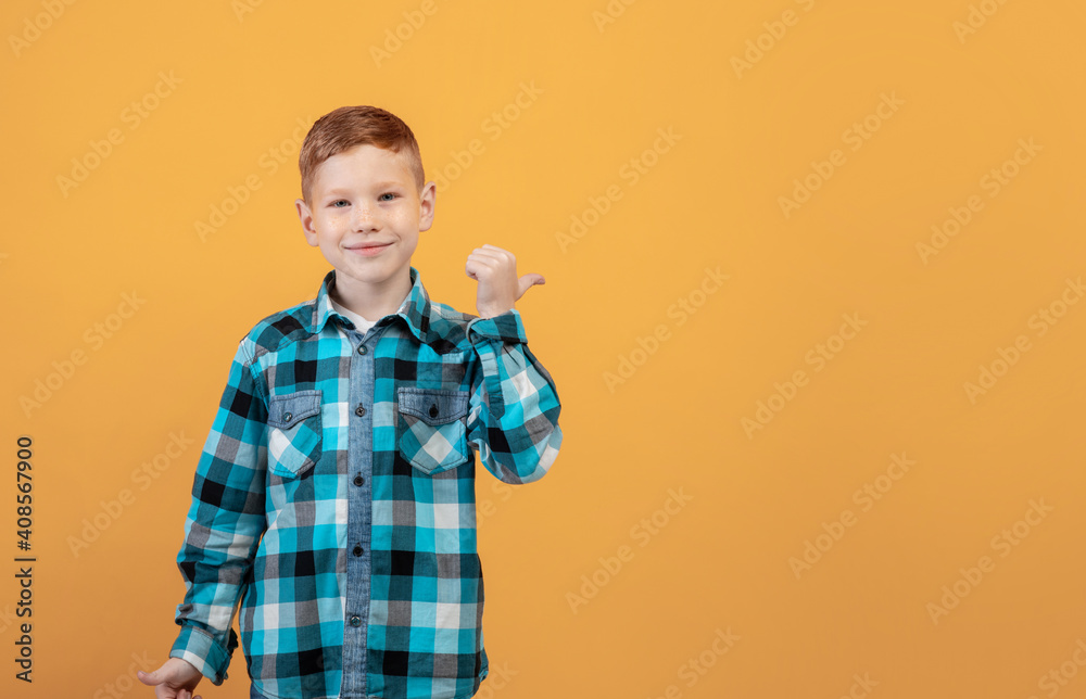 Smiling red-haired boy aiming at free space behind his back Smiling red-haired boy aiming at free space behind his back