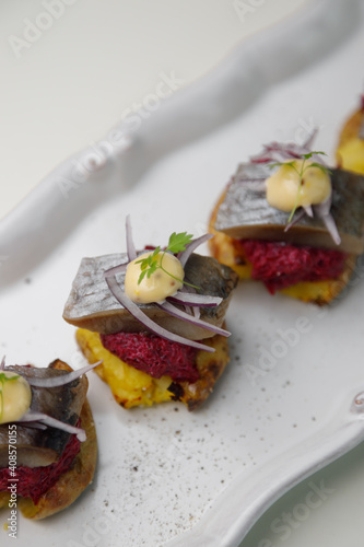 Herring canapes with pickled onions and baked potatoes. Appetizer on a platter close-up.