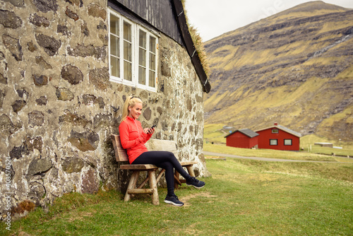Female athlete using smartphone near stone house