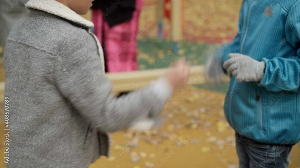 Two unrecognizable Caucasian boys playing rock-paper-scissors in autumn park on playground. Cheerful brothers having fun outdoors together. Happiness and childhood concept. Two unrecognizable Caucasian boys playing rock-paper-scissors in autumn park on playground. Cheerful brothers having fun outdoors together. Happiness and childhood concept.