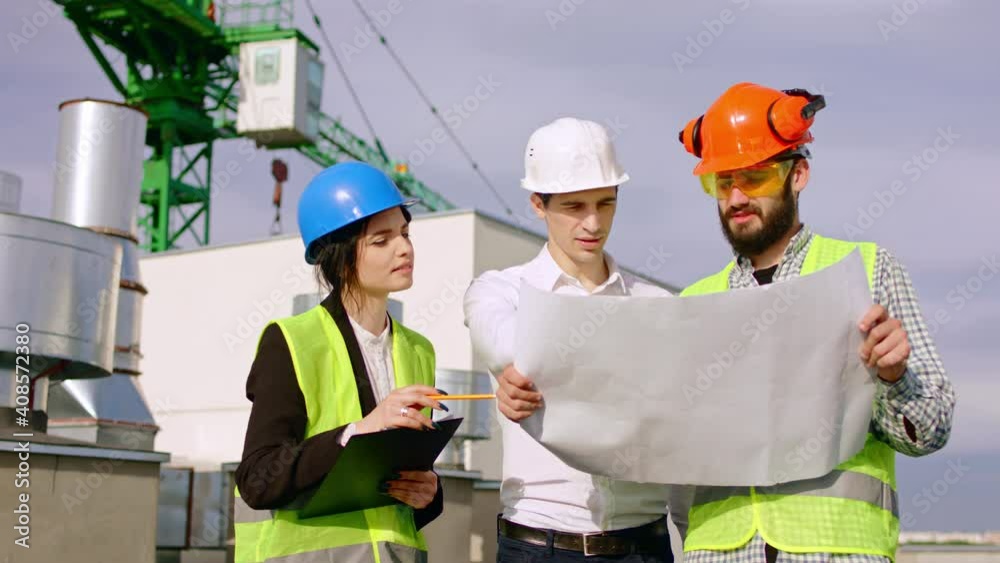 On the top of construction site businessman man and two diverse specialists lady and man they using a plan of construction analyzing some details. Shot on ARRI Alexa On the top of construction site businessman man and two diverse specialists lady and man they using a plan of construction analyzing some details. Shot on ARRI Alexa