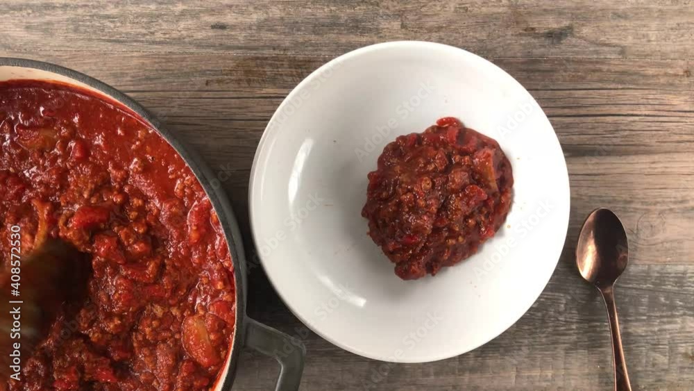 spooning pot of bean-less chili into bowl top view spooning pot of bean-less chili into bowl top view