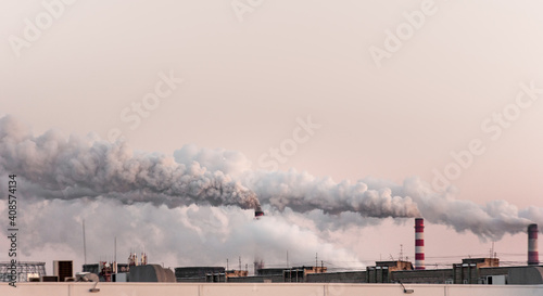copy space with industrial chimneys with heavy smoke causing air pollution on the pink and gray smoky sky background