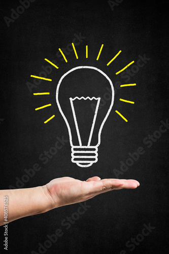 hand holding bulb drawn blackboard