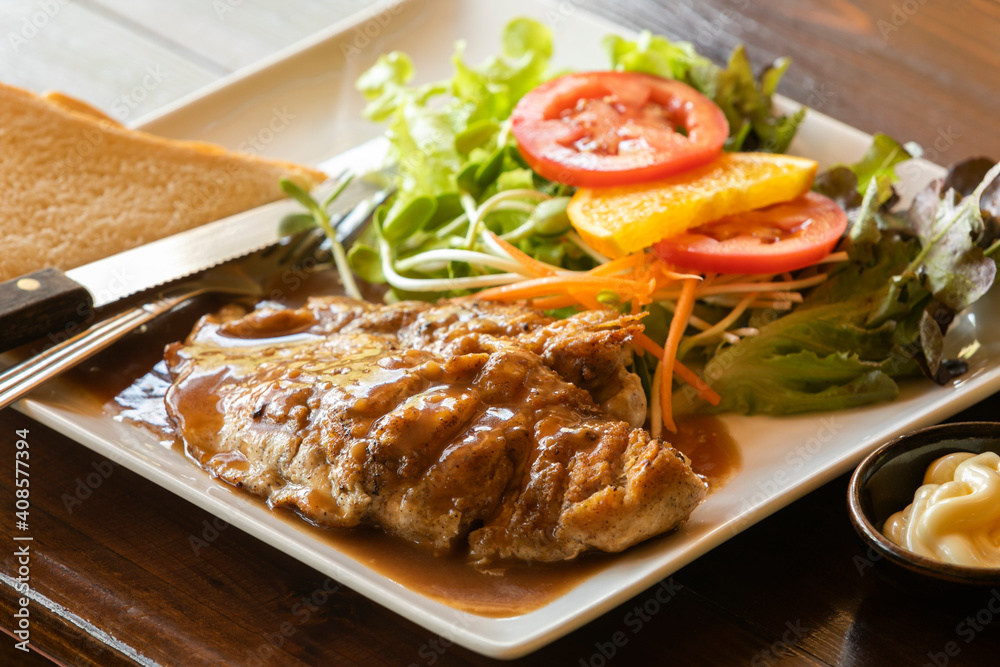 close up roasted chicken steak with gravy sauce, there are bread and salad with cream sauce on side dishes