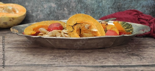 Roasted slices of pumpkin and cherry tomatoes on a silver tray