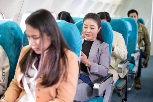 Businesswoman fasten seat belt while sitting on the airplane for safety flight. Comfortable and safe for traveling by air. The security system is rigorous. International Airlines. Long trip vacation