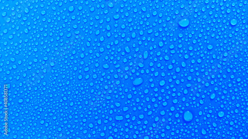 Small drops of water on a blue background, top view.