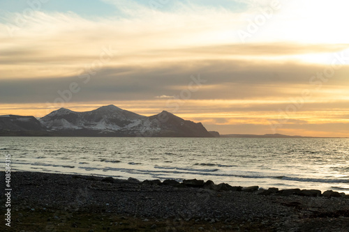 Llyn Peninsula   Wales. Sunset landscape on a crisp winters day. Beautiful view over the sea to distant moody  snowy mountains. Copy space.