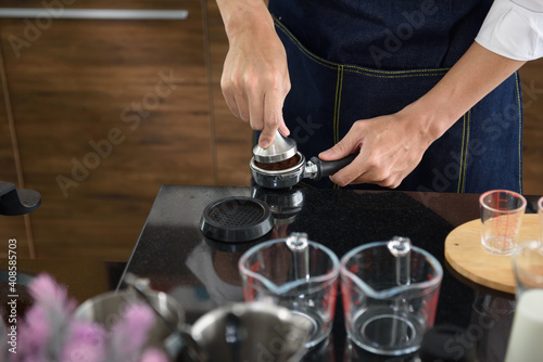 Close up hand of barista using tamper for preparing coffee in the coffee shop