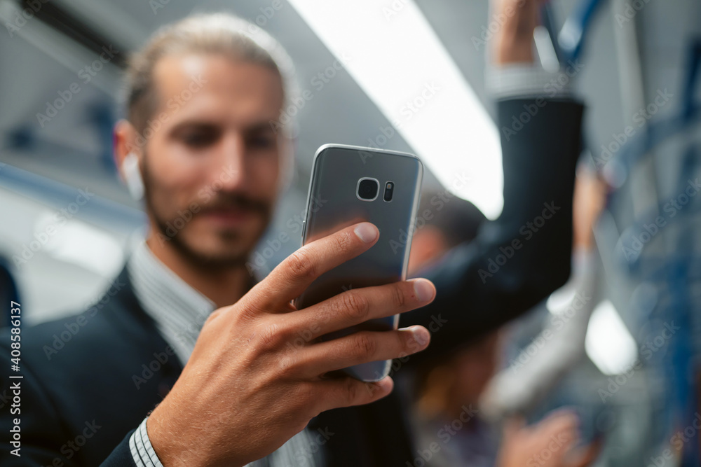 attractive man using his smartphone in subway train .